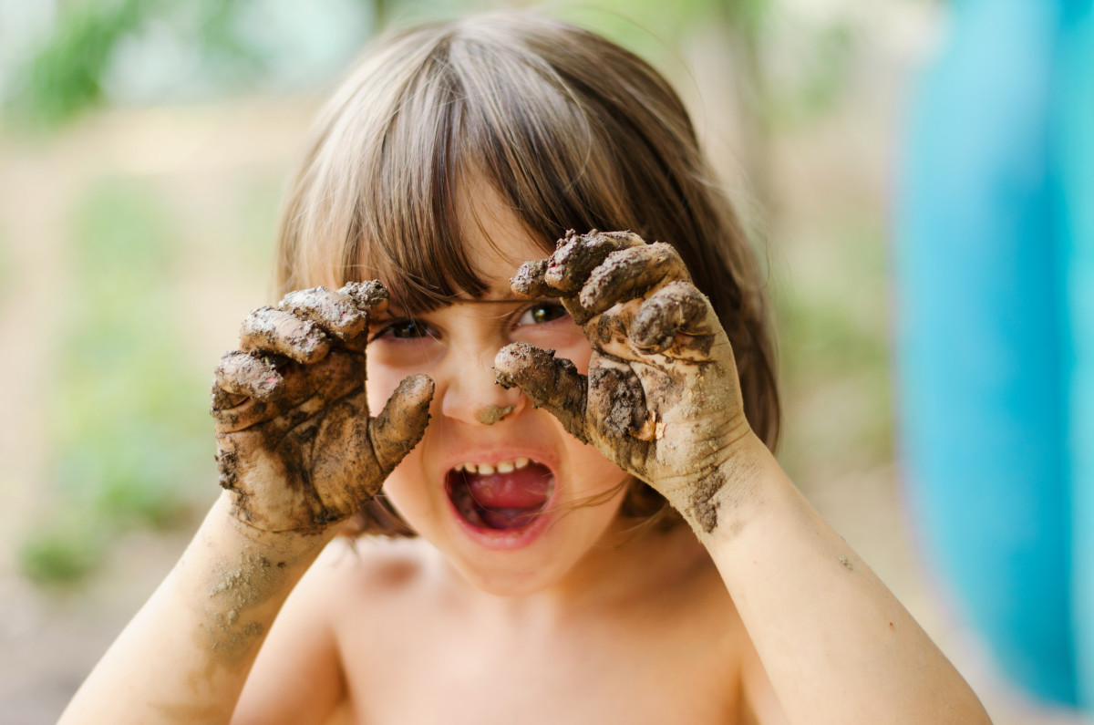 Barn med mudder på hænderne