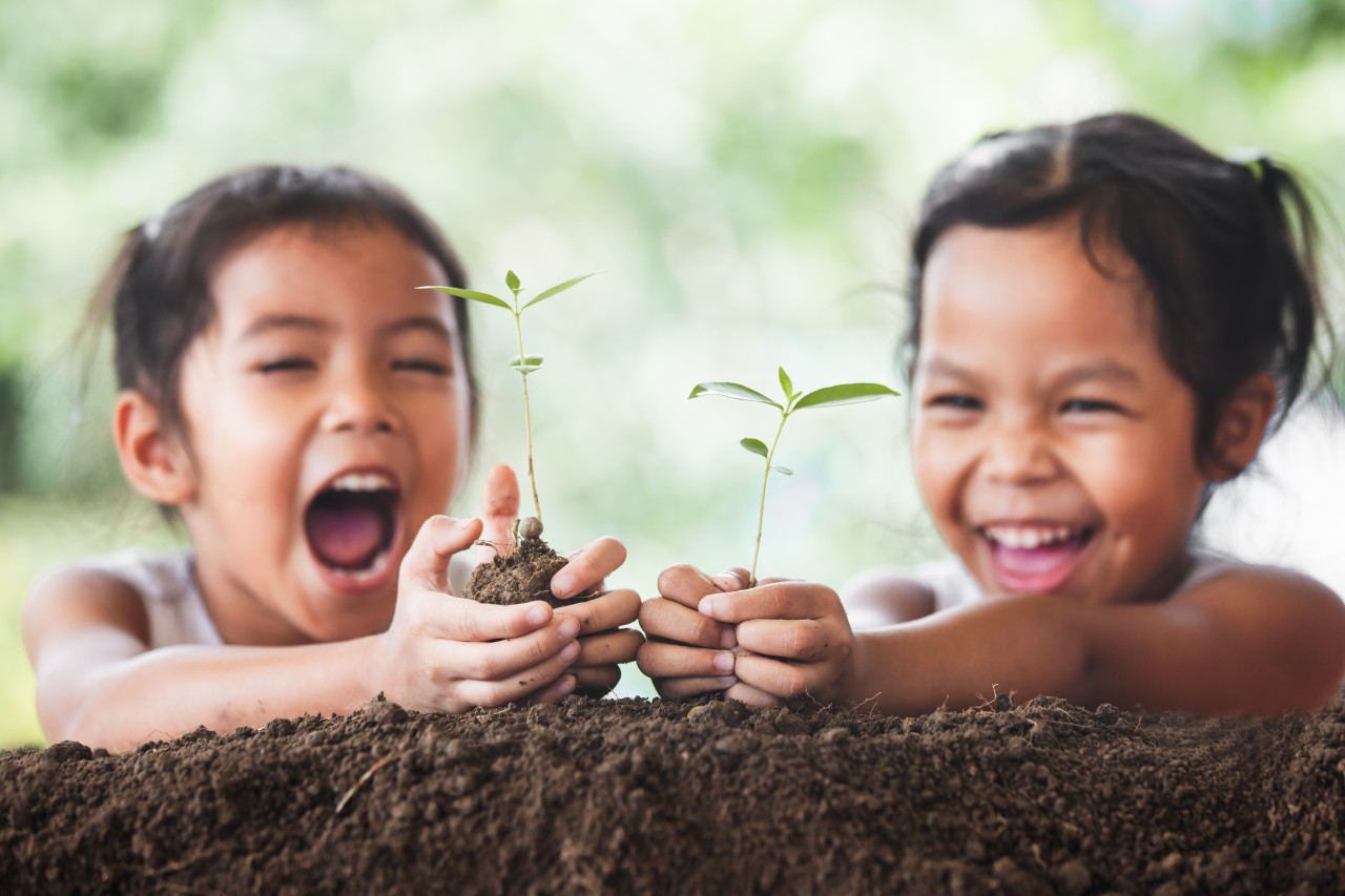 To børn smiler til en plante, der vokser